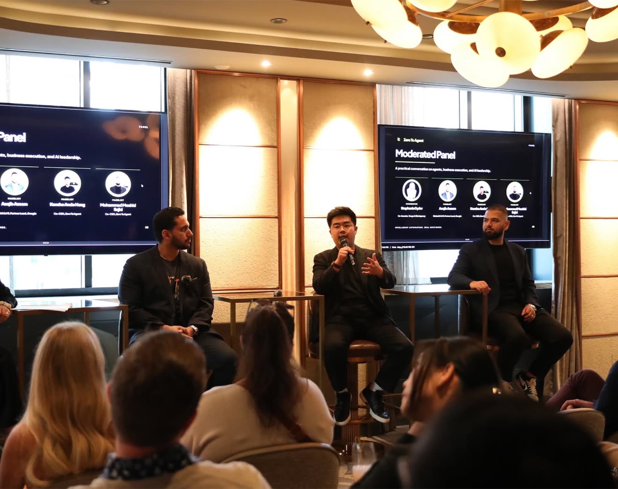 The ParcWork team on stage at an in-person panel, one of them speaking into a microphone, with a seated audience in front of them